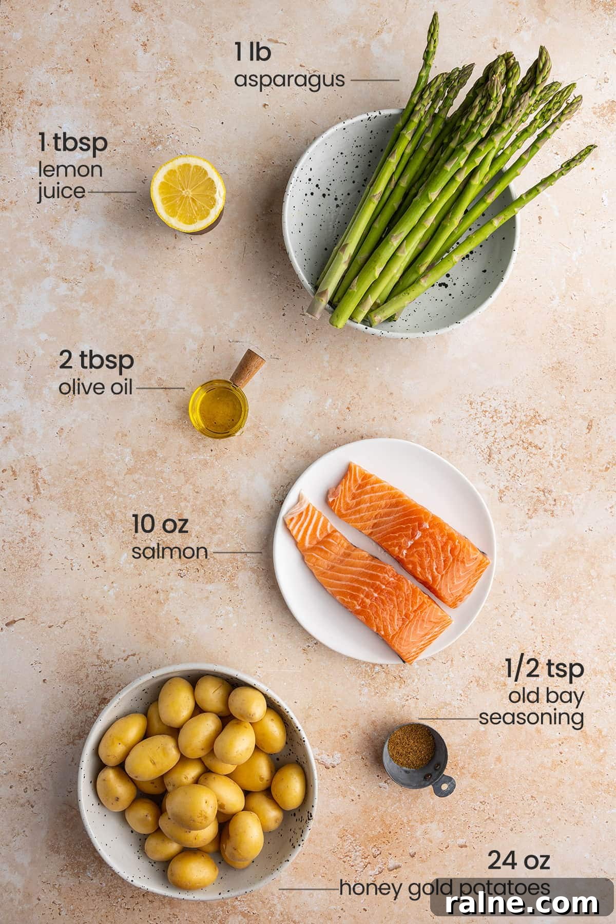 all ingredients for sheet pan salmon, asparagus and potatoes - lemon juice, asparagus, olive oil, salmon, old bay seasoning, honey gold potatoes