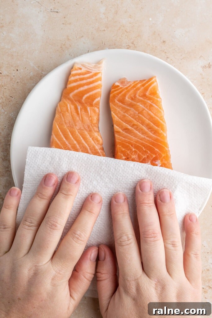 Patting salmon dry before seasoning and roasting it.