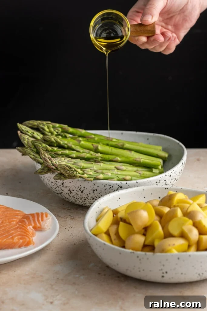 Adding olive oil to asparagus, potatoes, and salmon.