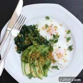 Poached eggs with avocado, spinach & crispy quinoa on a white plate with a knife and fork and on a black background
