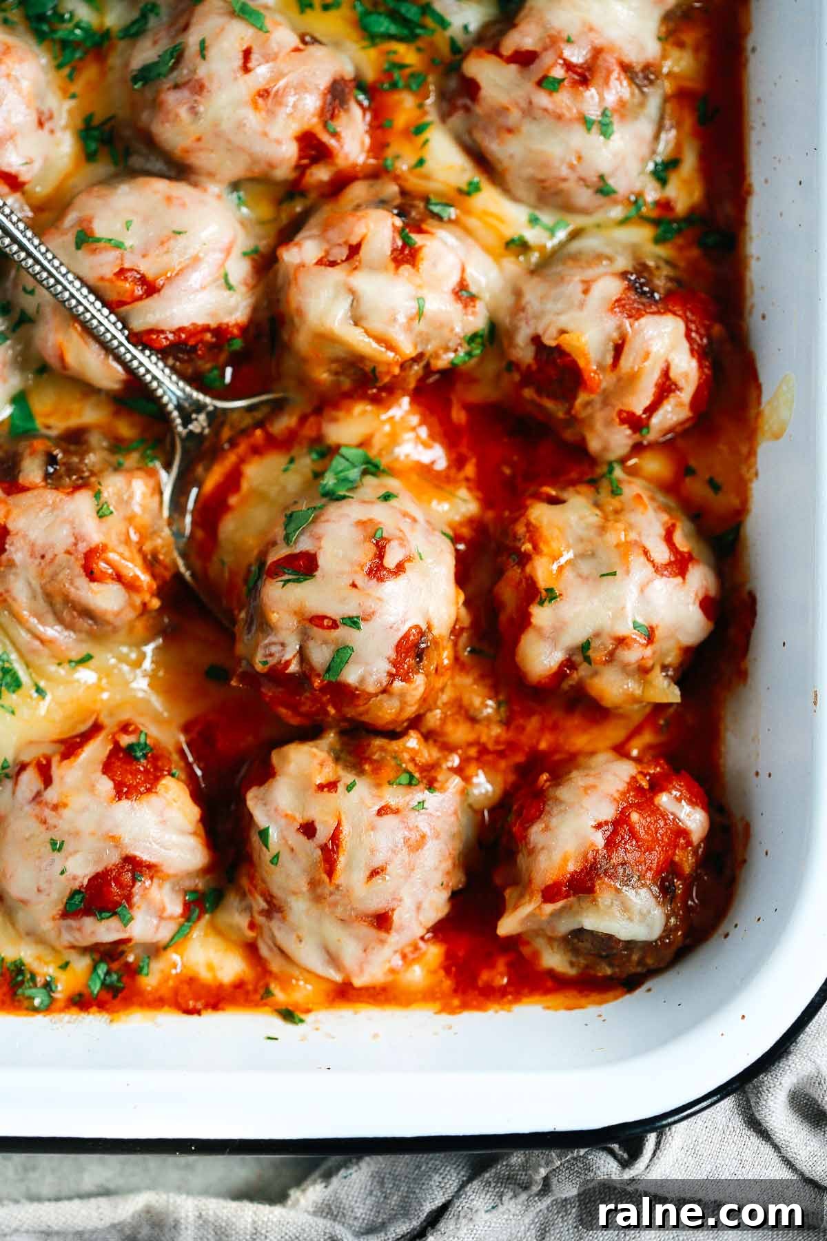 Cheesy Baked Meatball Casserole with Marinara and Pasta 2 Close up of Baked Meatballs Casserole with a spoon lifting one meatball
