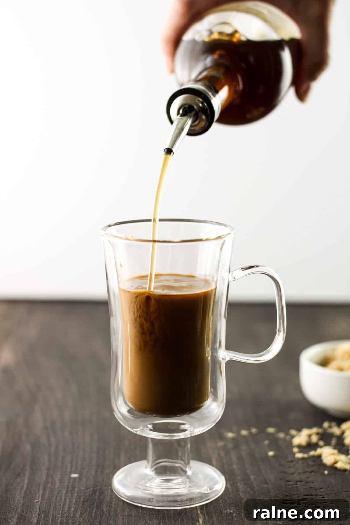 Brown Sugar Simple Syrup Recipe for Cocktails and Coffee 6 A coffee drink with a bottle of brown sugar syrup pouring in syrup.