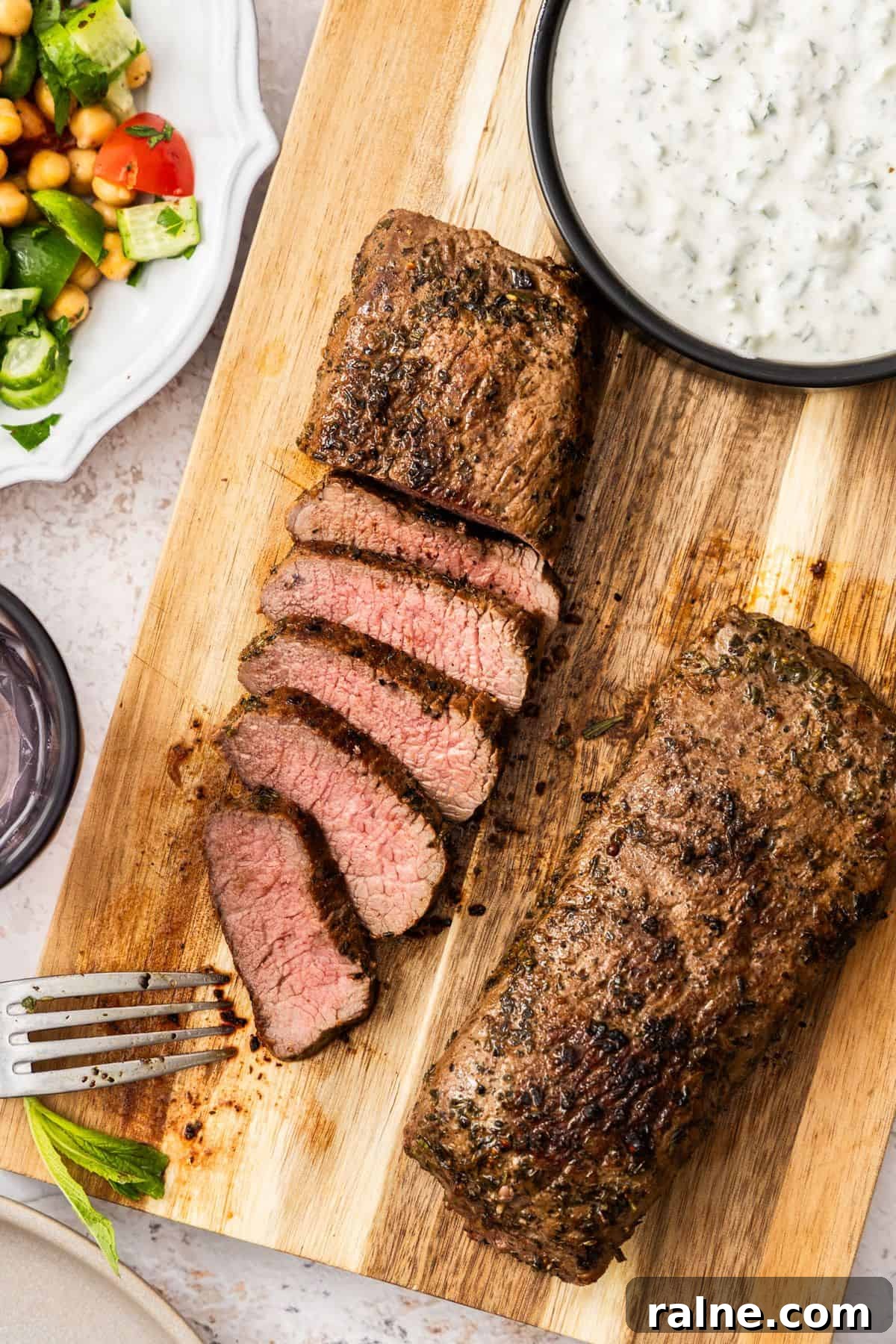 Marinated Lamb Backstrap Recipe: Juicy Grilled Lamb Backstrap 6 Cooked lamb on a wooden board with yoghurt sauce.