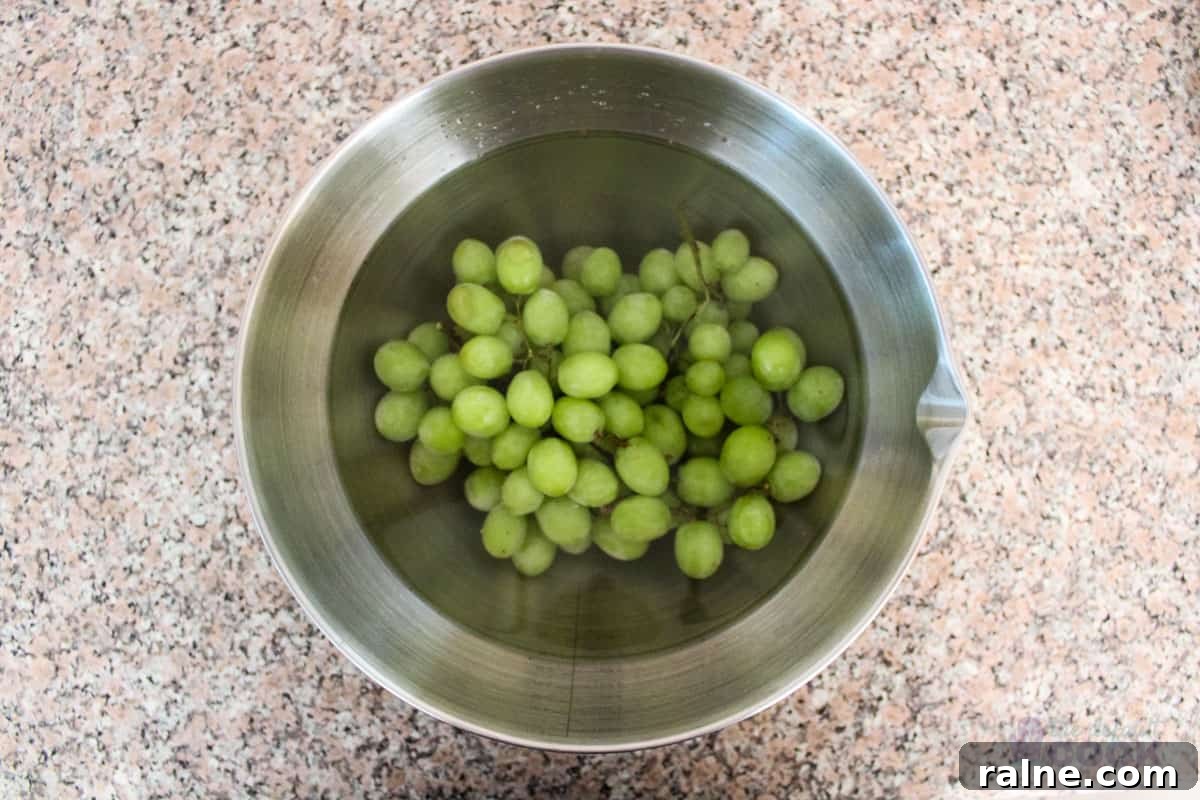Colorful Fruit Platter with Creamy Yogurt Dip 4 A bowl sitting on a kitchen counter filled with green grapes covered with water and vinegar.