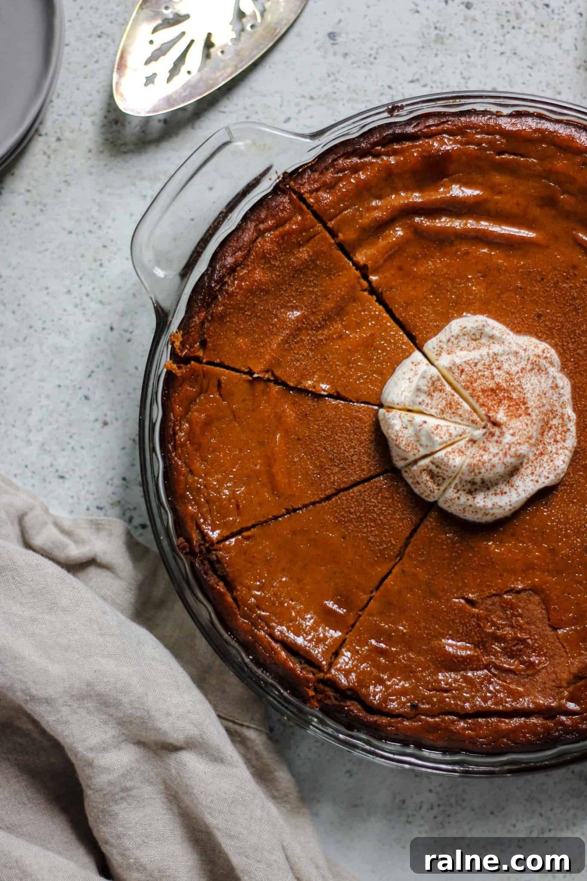 flatlay photo of a pumpkin pie with whipped cream and three cut slices