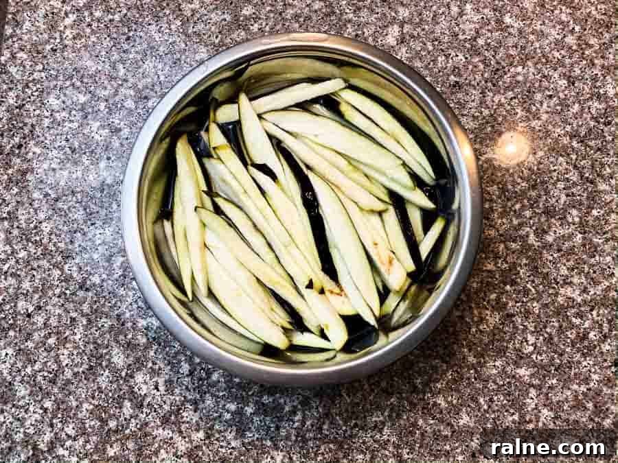 Summer Eggplant Jerky Recipe: Crispy Savory Plant-Based Snack 5 eggplant slices soaking in salt water in silver bowl
