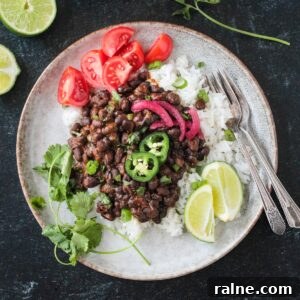 Zesty Spiced Black Beans Recipe for Bold Flavor 13 Serving of spicy seasoned black beans over coconut rice with a side of tomatoes.