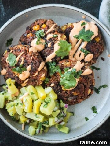 Four black bean patties on a plate with pineapple avocado salsa and chipotle crema.