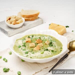 Creamy Pea and Spinach Soup in a bowl with croutons on top and a spoon on the side.