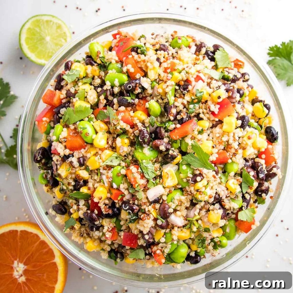 Southwest Quinoa Salad with Black Beans, Corn & Lime Dressing 3 large glass bowl filled with colorful quinoa salad. half a lime, half an orange and fresh cilantro on the white counter surrounding the bowl.