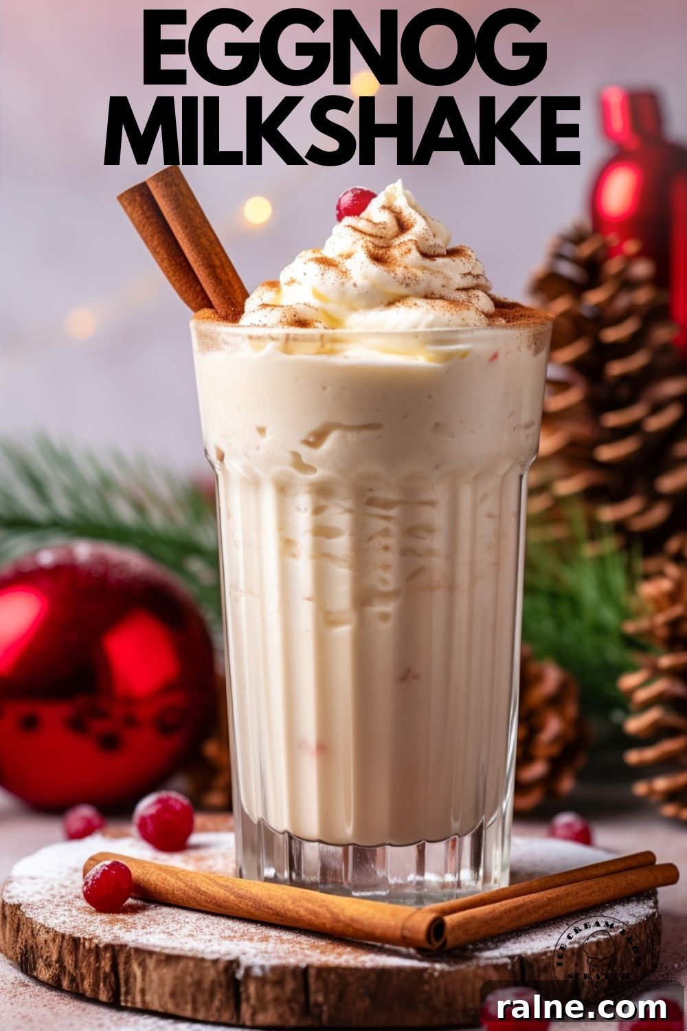 Creamy Eggnog Milkshake Recipe for the Holidays 5 An eggnog milkshake in a tall glass, garnished with cinnamon sticks, whipped cream, and a cranberry. In the background are red ornaments, greenery, and pinecones. Text overlay says "eggnog milkshake" in capital letters