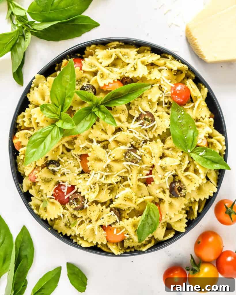 Creamy Pesto Pasta Salad with Fresh Tomatoes and Basil 2 pesto pasta salad in a serving bowl with basil leaves on top.