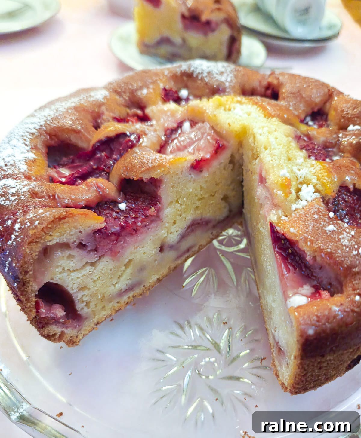 Light Mascarpone Strawberry Cake Without Butter — Moist Summer Dessert 3 A strawberry mascarpone cake on a glass platter with a slice removed to show the inside of the cake.