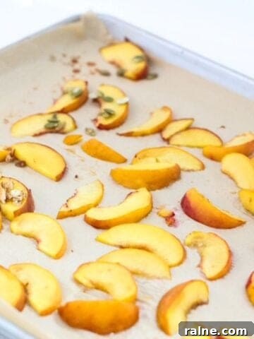 Roasted peach slices on a lined baking sheet.