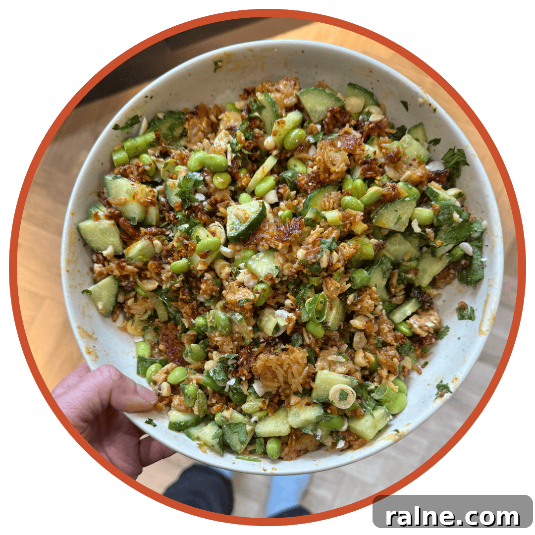 Crispy Rice Salad with Crunchy Veggies and Tangy Dressing 3 A hand holding a bowl of crispy rice salad.