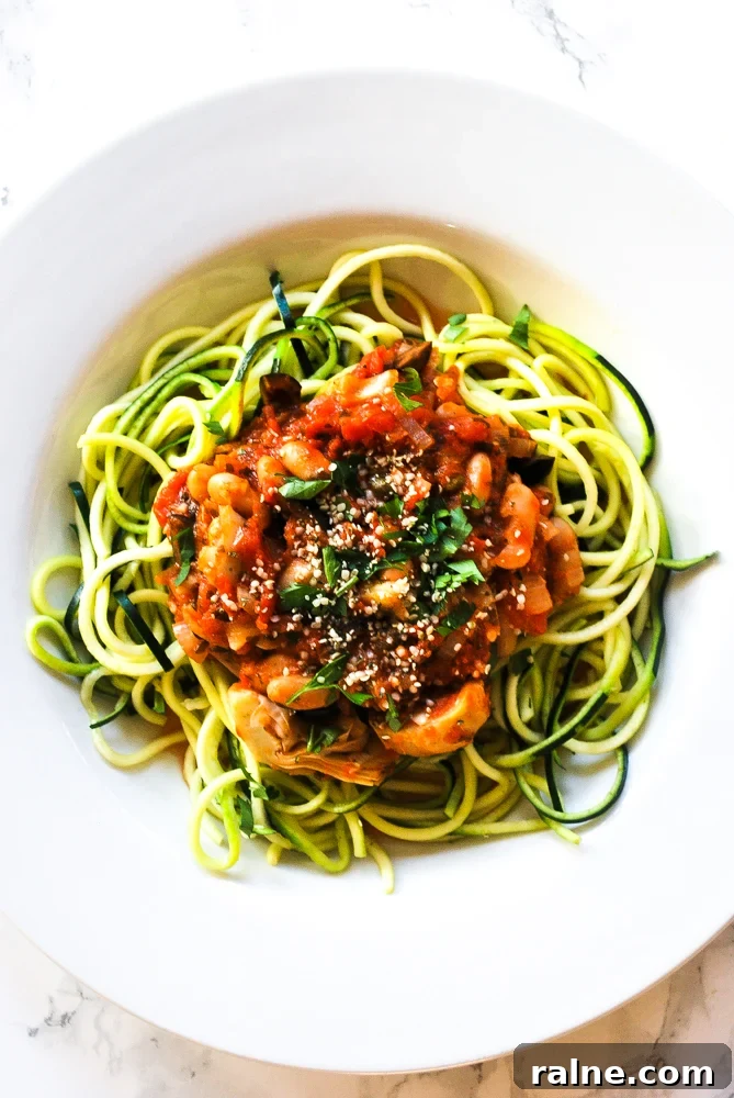a bowl of vegan puttanesca zoodles with white beans