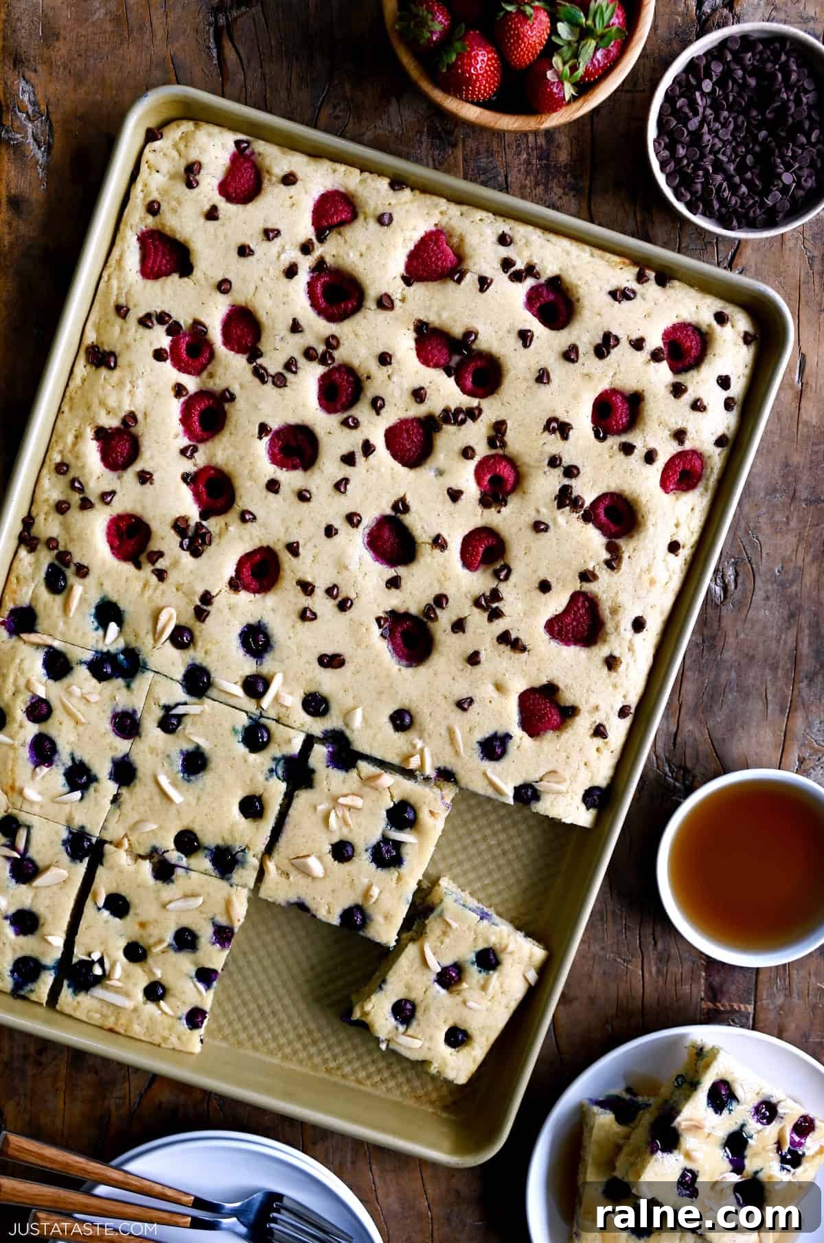 Sheet pan pancakes with one half blueberries and slivered almonds, and the other half raspberries and mini chocolate chips.