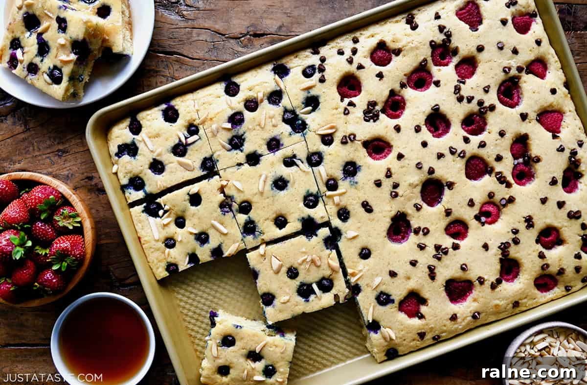 A sheet pan pancake with berries cut into squares.