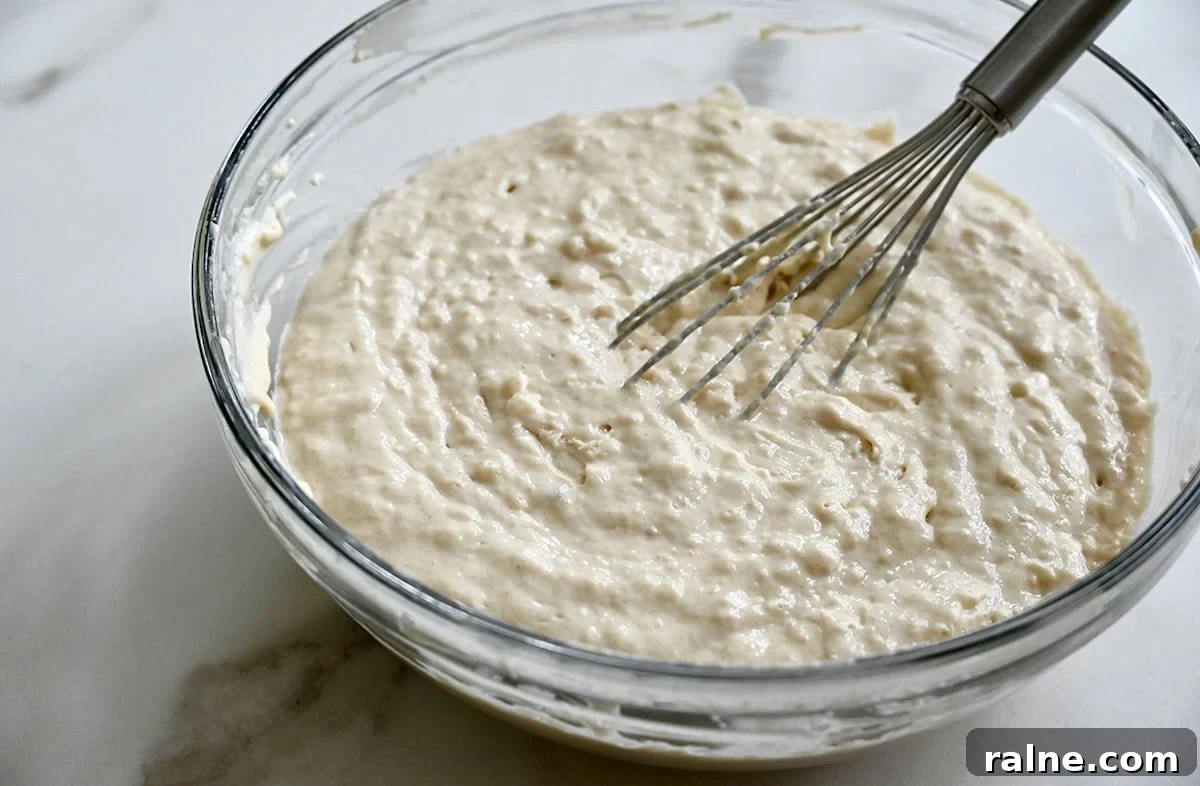 Lumpy sheet pan pancake batter in a glass bowl with a whisk.