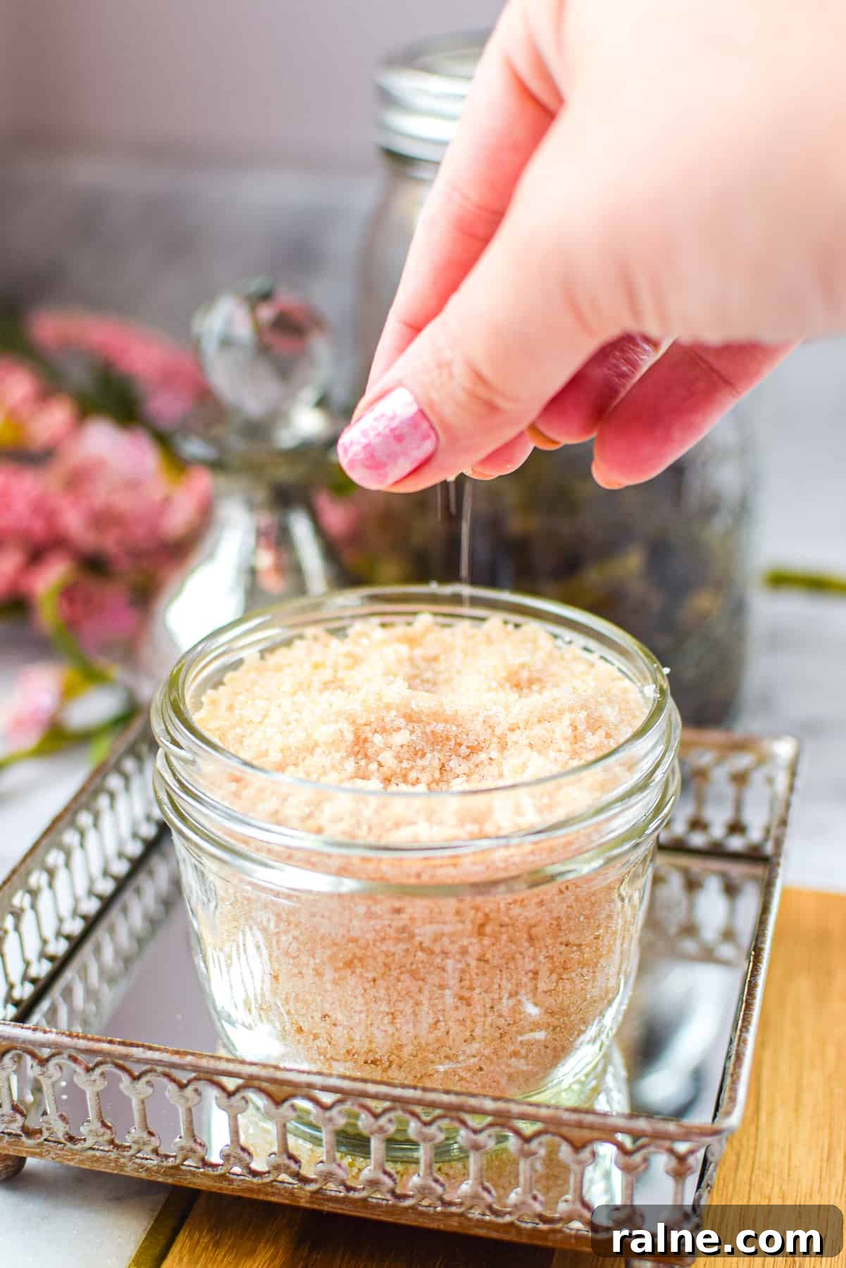 A hand sprinkling cannabis salt into a mason jar
