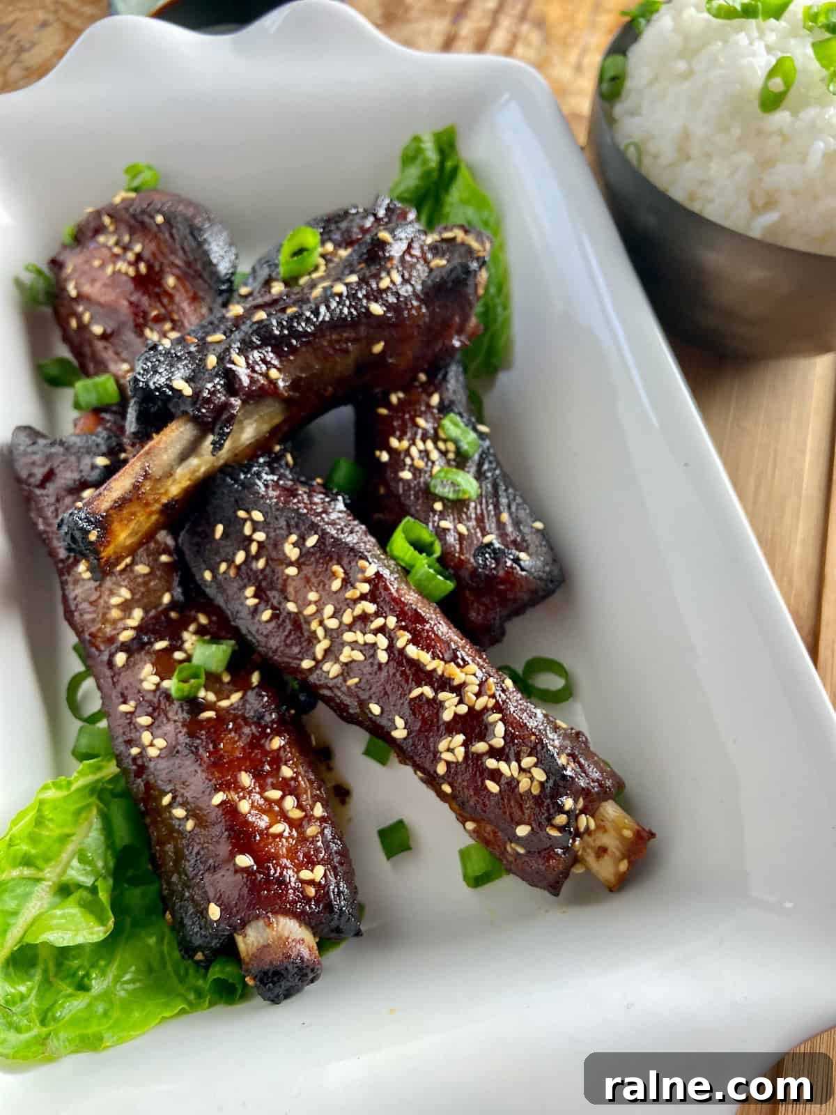 Sticky Asian-Style Pork Spareribs Recipe 2 Asian sticky ribs in a white shallow serving platter.
