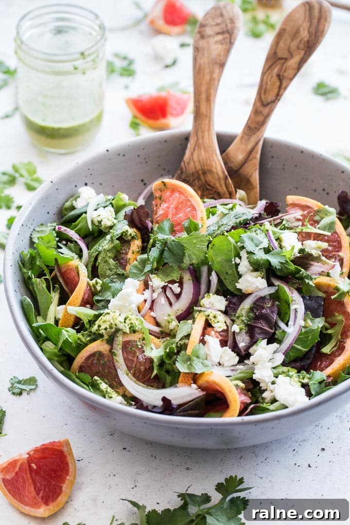 Grapefruit Salad with Cilantro and Goat Cheese in a large grey bowl with a jar of cilantro dressing in the background.