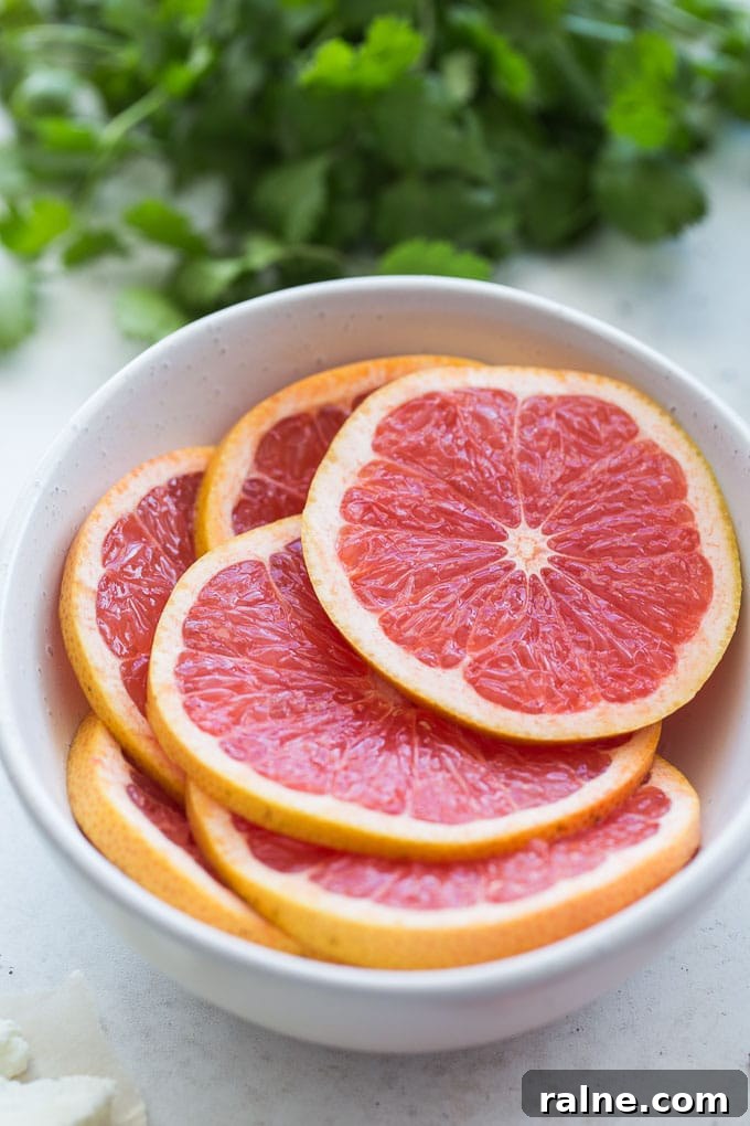 Up-close view of pink grapefruit slices in a white bowl.
