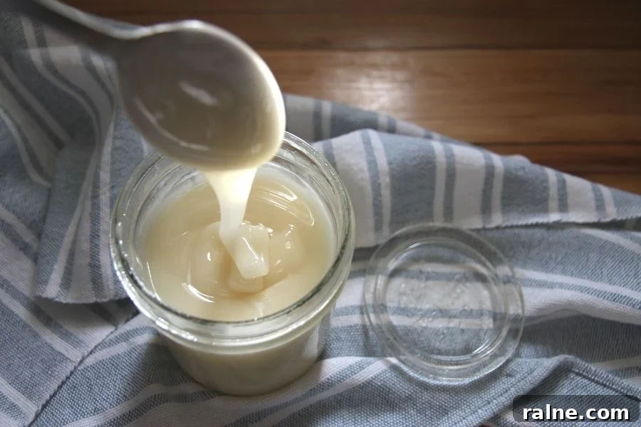 How to Make Smooth Creamed Honey at Home 2 creamed honey being drizzled into a jar with a spoon