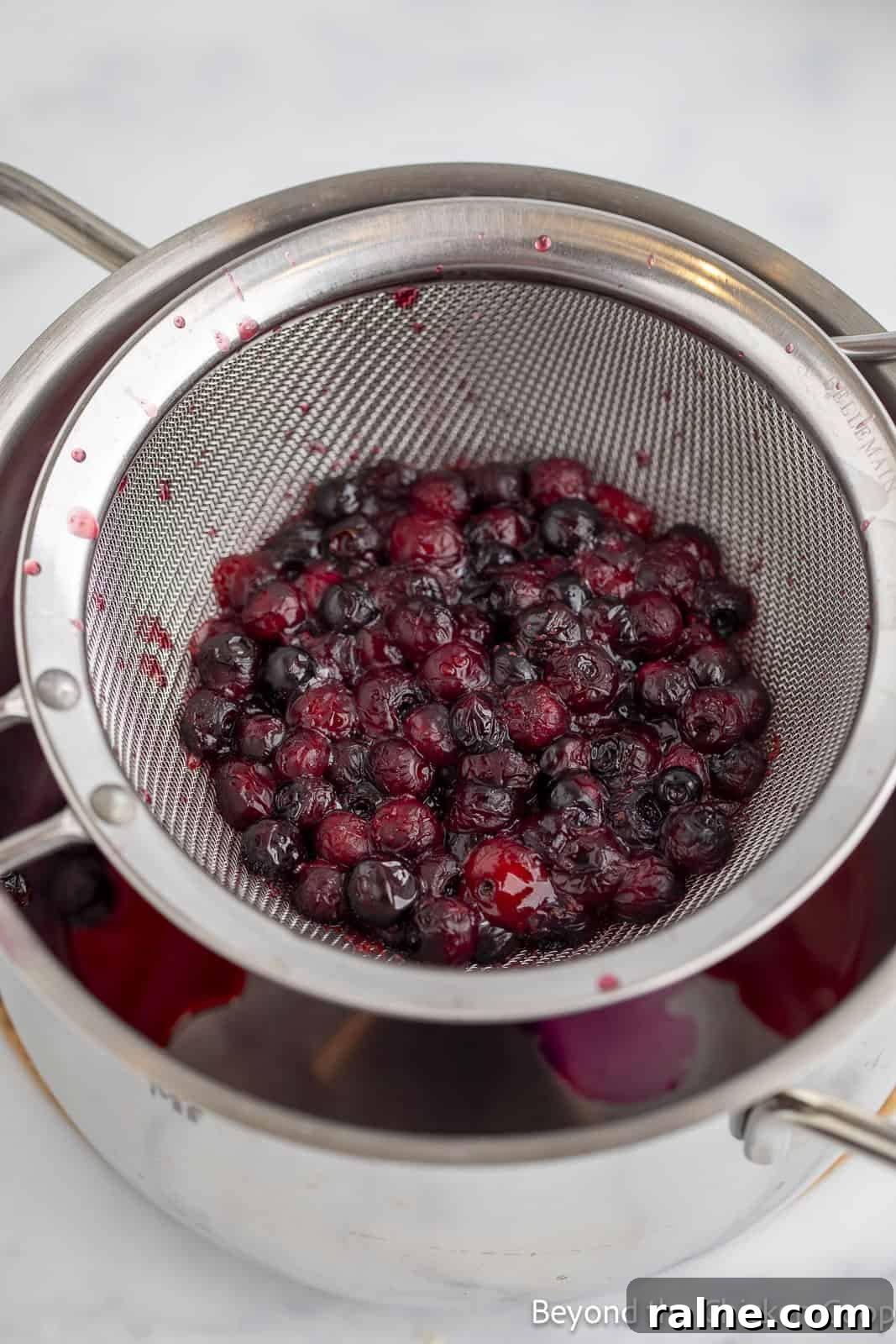 Huckleberry Lemonade Recipe: Refreshing Summer Drink with Fresh Berries 6 Strained huckleberries in a colander.