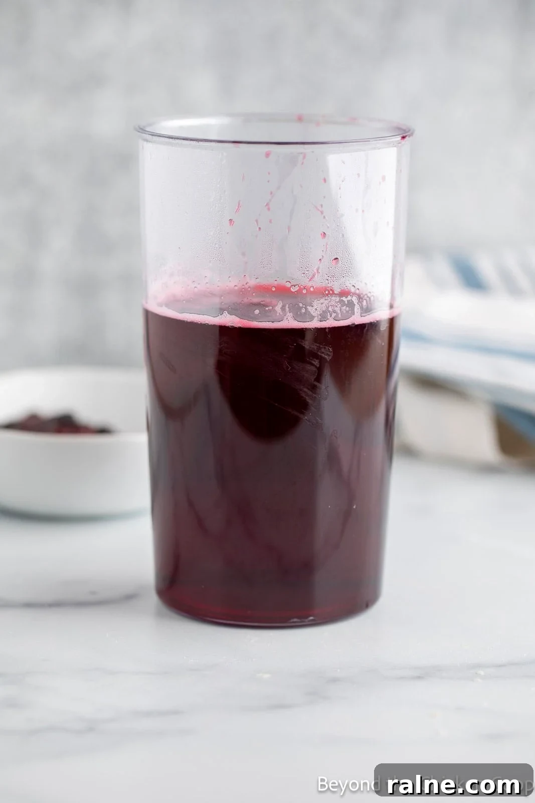 Huckleberry Lemonade Recipe: Refreshing Summer Drink with Fresh Berries 7 Huckleberry simple syrup in a tall plastic container.