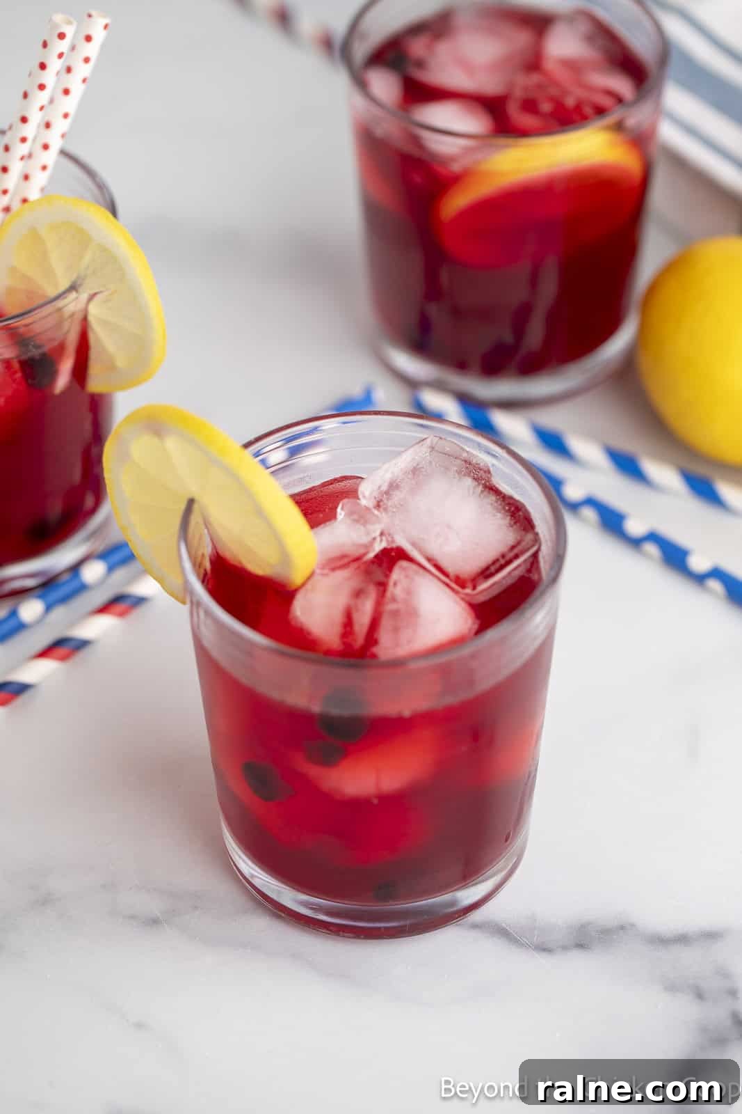 Huckleberry Lemonade Recipe: Refreshing Summer Drink with Fresh Berries 9 Huckleberry lemonade in a glass filled with ice and a lemon slice.
