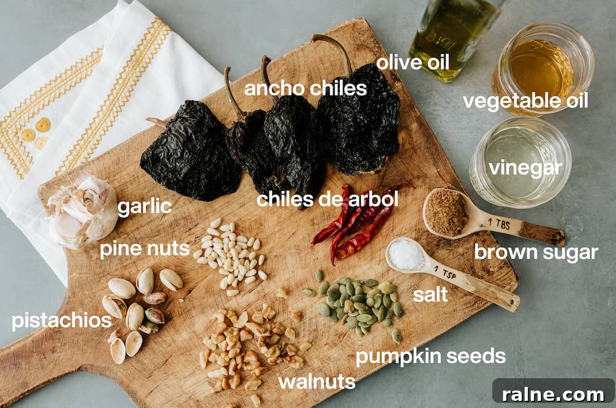 cutting board with labeled ingredients to make salsa macha -- dried chile pods, nuts, seeds, and spices.