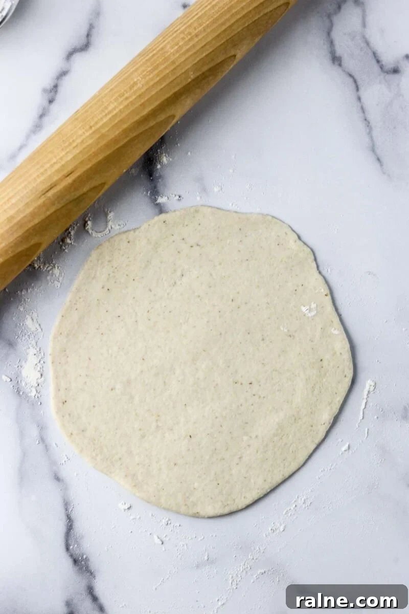 Soft Swedish Tunnbröd Recipe: How to Make Traditional Flatbreads 7 Flatbread dough rolled out on a marble counter with a rolling pin.