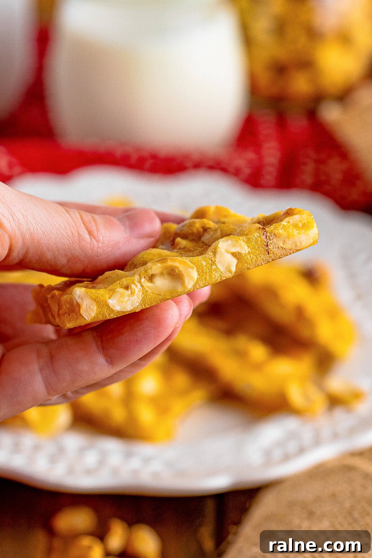 a hand holding up a piece of Microwave Peanut Brittle in air