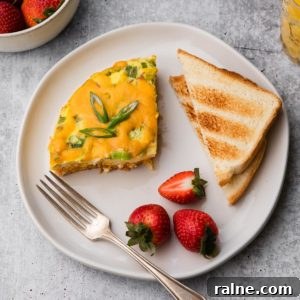 A plate of breakfast casserole, toast, and strawberries.