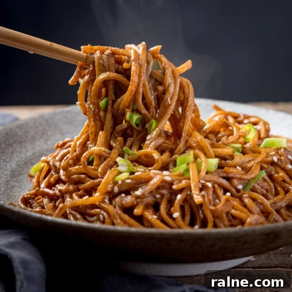 Singapore Stir-Fry Noodles with Curry and Shrimp 13 Square image of sesame noodles in a bowl, topped with spring onions and sesame seeds.