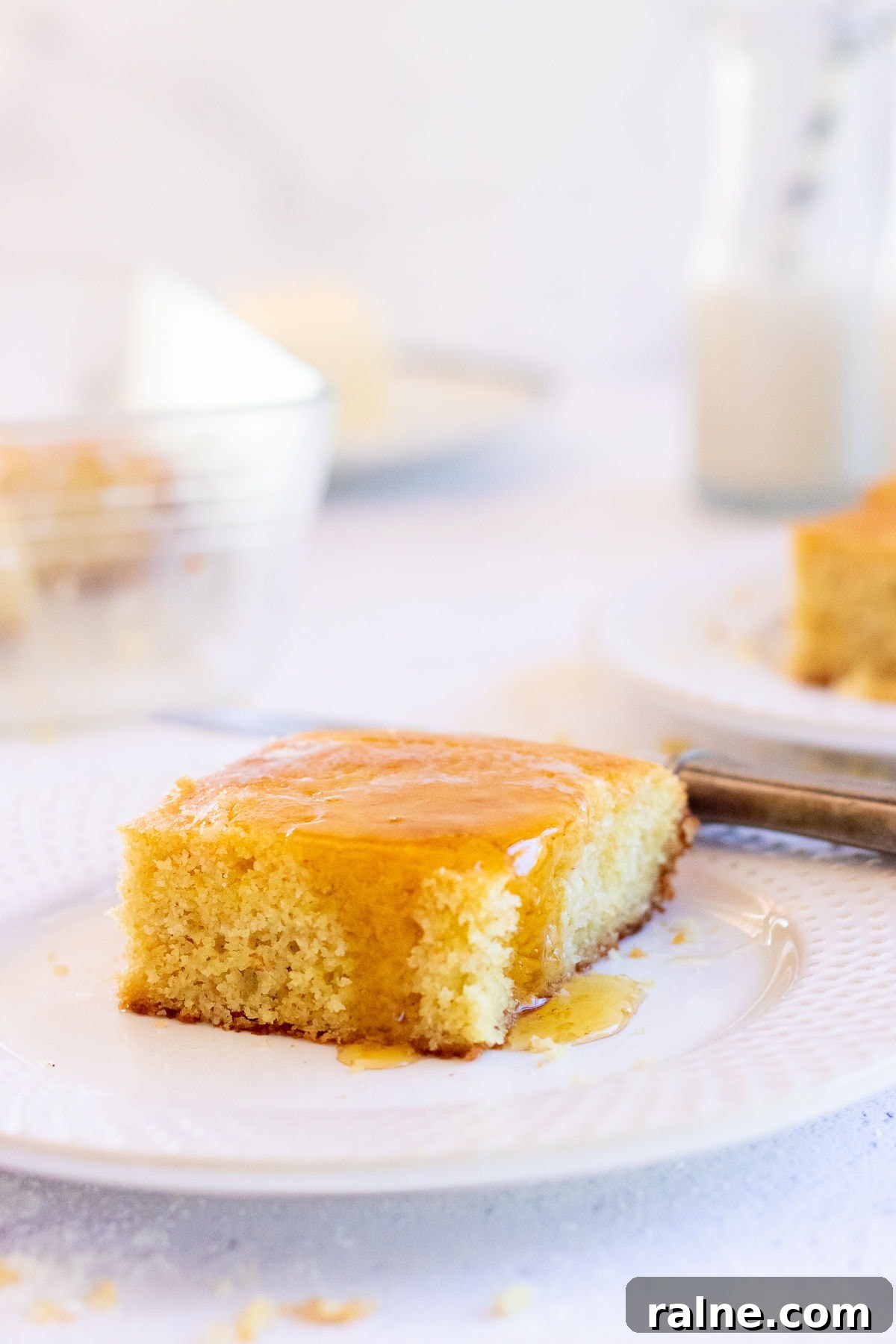 Square of buttermilk cornbread with honey dripping down the sides.