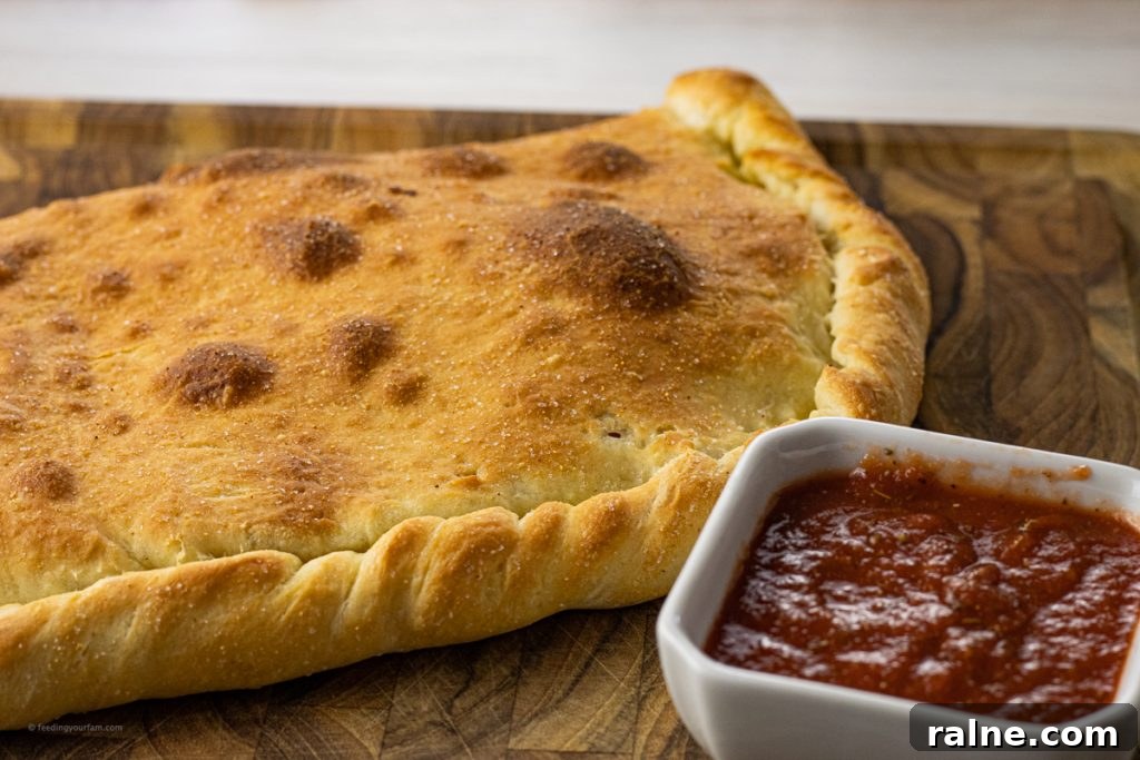 pizza dough and a cooked calzone on a wooden cutting board