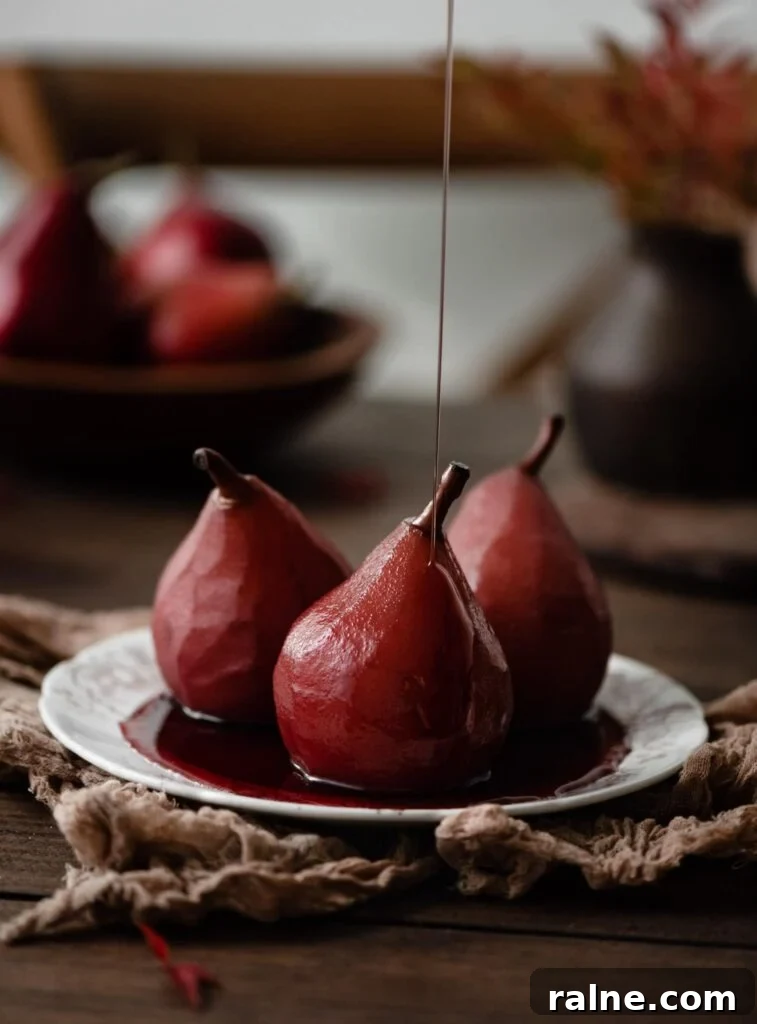 Wine-Poached Pears Recipe: Elegant Dessert with Red Wine Glaze 3 Red wine pears on plate with a drizzle of honey.
