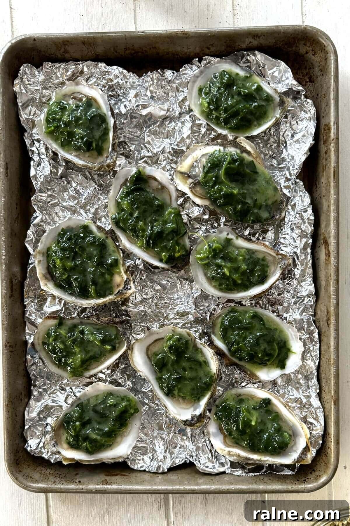 Oysters Rockefeller with Frozen Creamed Spinach: Quick Recipe 8 Shucked oysters topped with creamed spinach on a baking sheet.