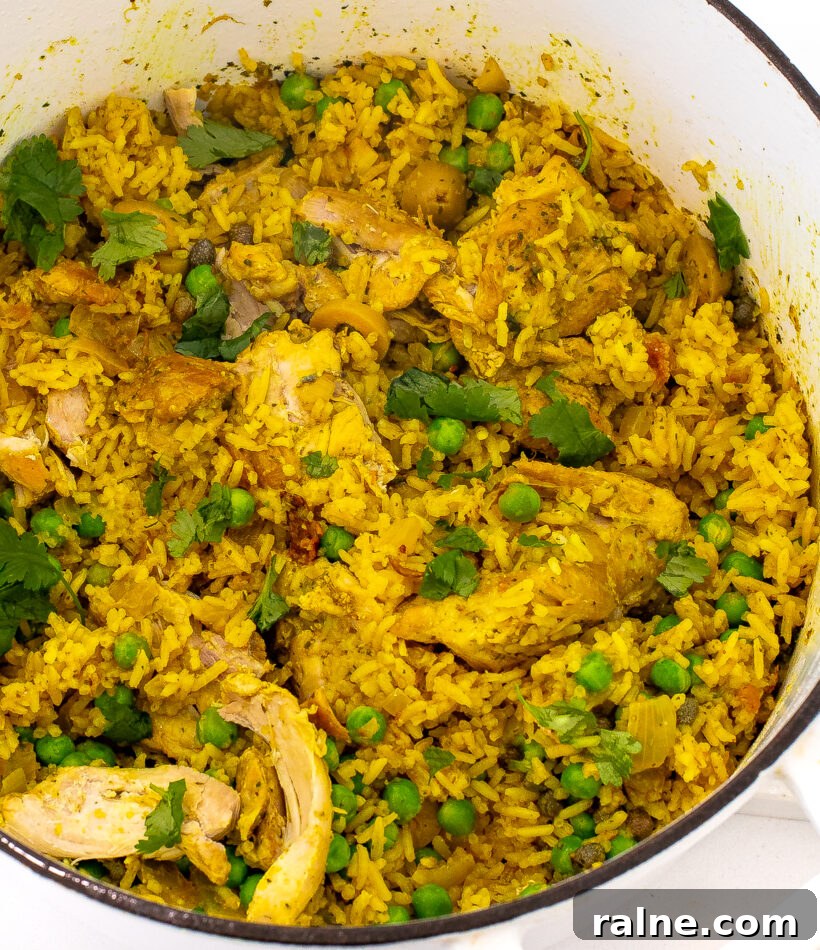Authentic Latin-Style Chicken and Rice Recipe 2 Chicken and rice in a pot with peas and cilantro.
