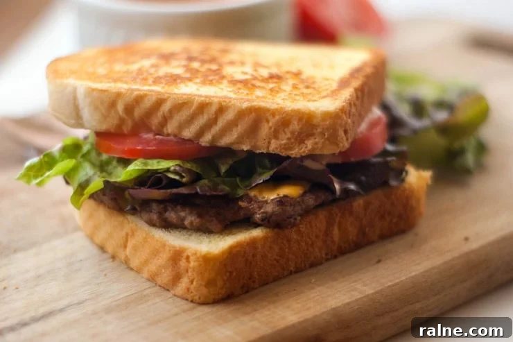 Easy Texas Toast Griddle Burger with tomatoes and lettuce on a wooden board.