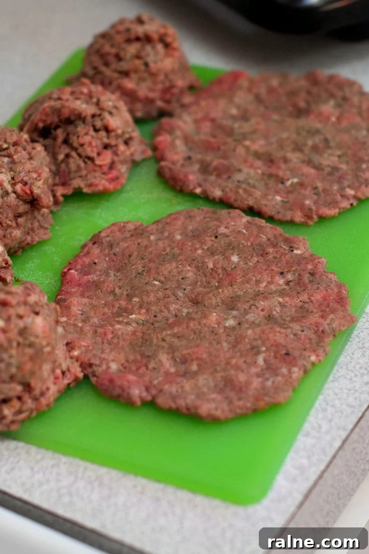Seasoned Burger Patties on a green cutting board.