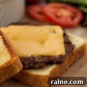 Texas Toast Griddle Burger patty on buttered bread on a wooden board.