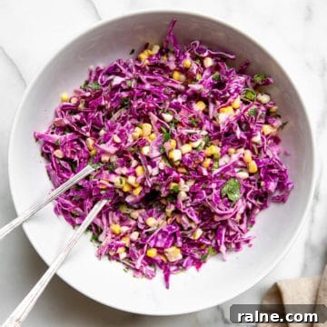 Red cabbage coleslaw in a bowl with serving spoons.