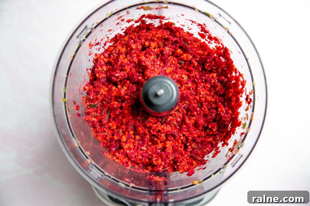 Process shot showing the ingredients for the veggie beet burgers chopped up in a food processor.