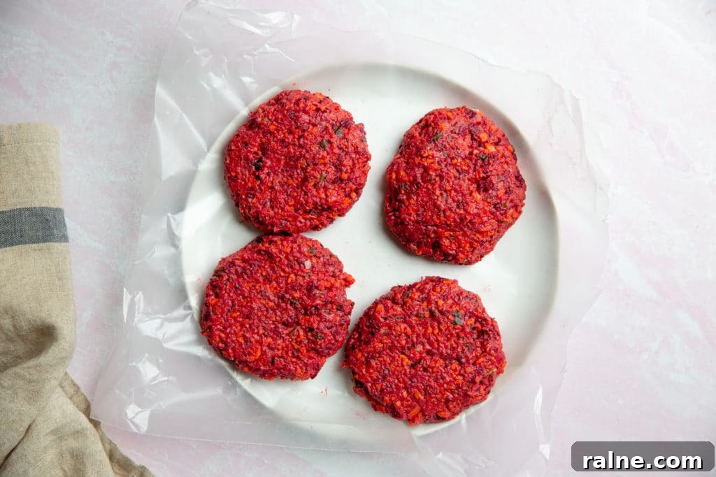 Four uncooked beet burger patties on a plate.