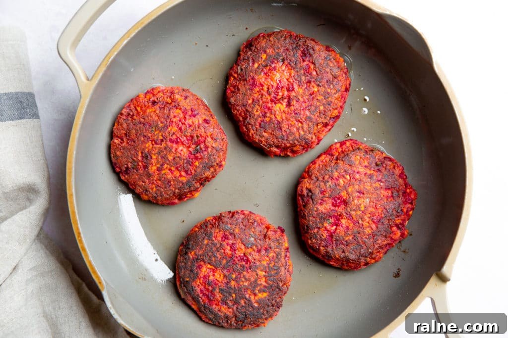 Four cooked veggie burgers in a skillet.