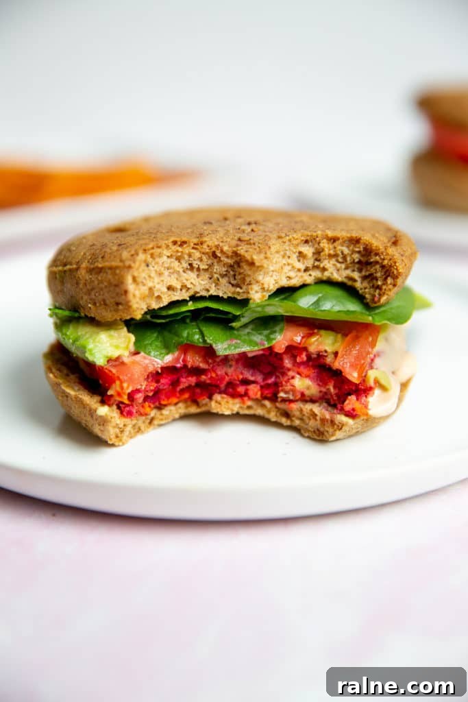 A gluten free veggie beet burger on a plate with two bites removed.