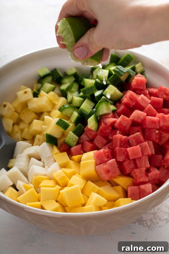 Authentic Mexican Fruit Cups (Vasos de Fruta) — Street Snack Recipe 5 Squeezing lime juice over a bowl of chopped fruit